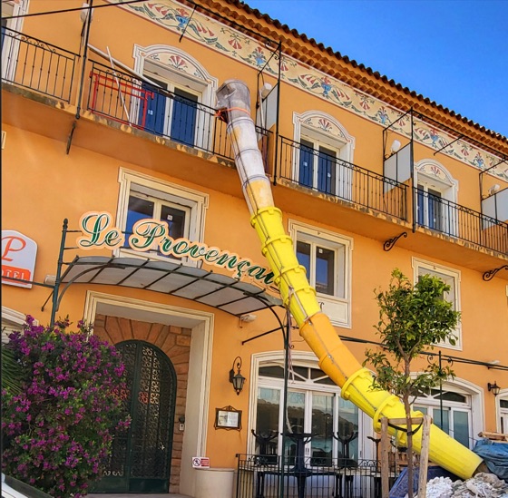 Un long toboggan jaune qui sort d’une façade d’hôtel, comme une trompe
