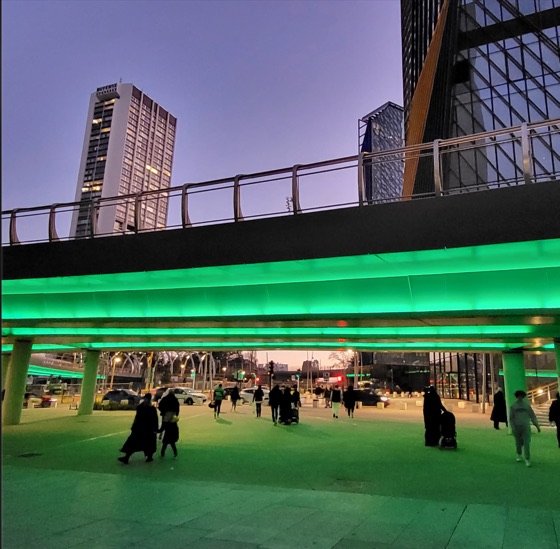 Une passerelle urbaine baignée de lumière verte fluo